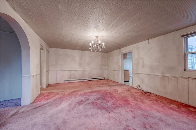 empty room featuring a chandelier, light carpet, and a baseboard heating unit