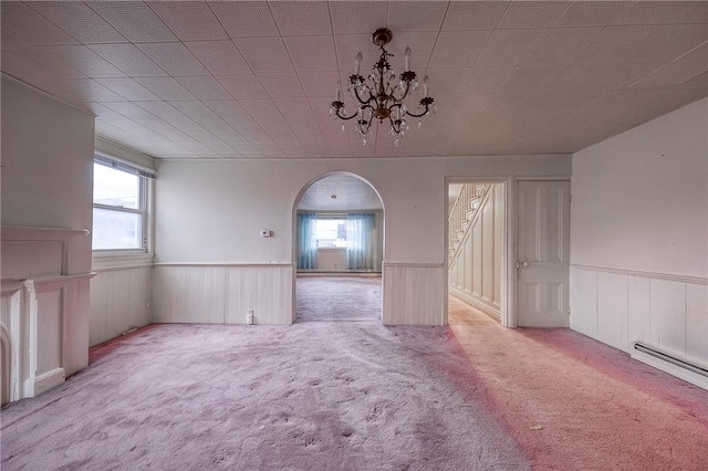 carpeted spare room with baseboard heating and a chandelier