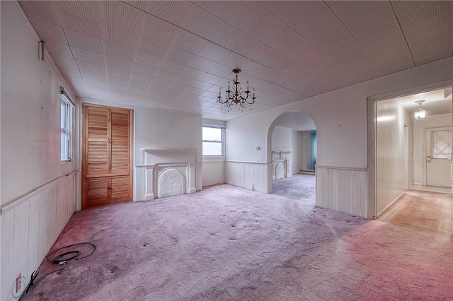 unfurnished living room featuring light carpet and a chandelier