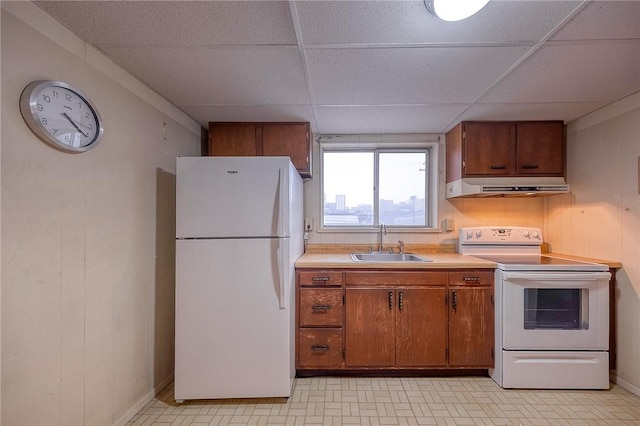 kitchen with a paneled ceiling, wood walls, sink, and white appliances