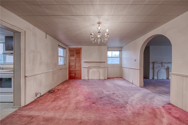 unfurnished living room featuring light carpet, a chandelier, and a fireplace