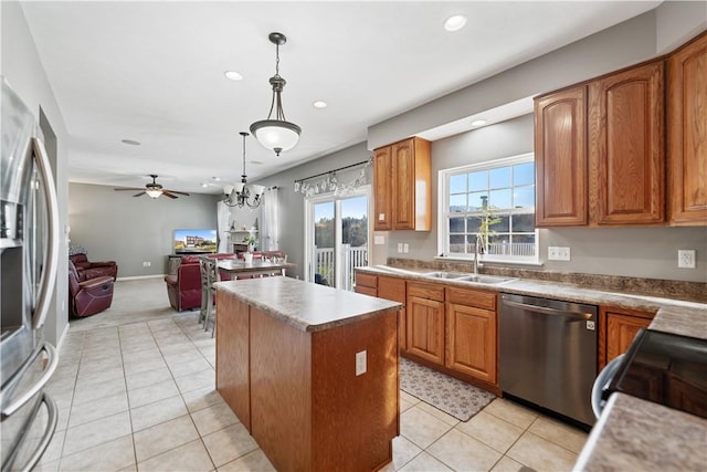 kitchen with sink, a center island, stainless steel appliances, decorative light fixtures, and ceiling fan with notable chandelier