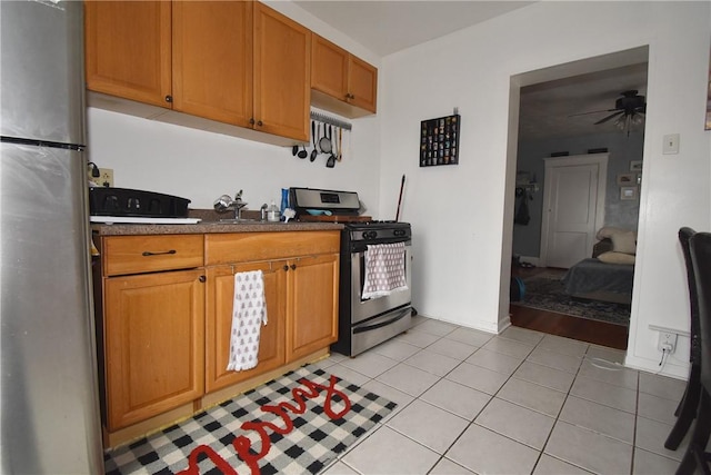 kitchen featuring stainless steel refrigerator, ceiling fan, sink, light tile patterned floors, and range