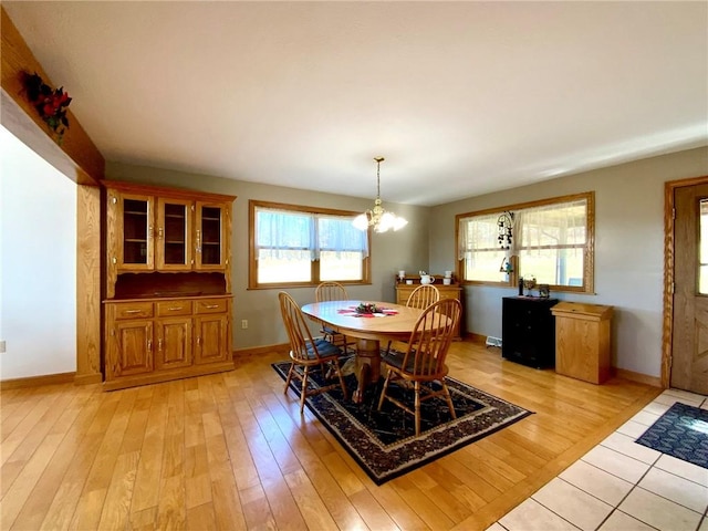 dining area with light wood-type flooring and a notable chandelier