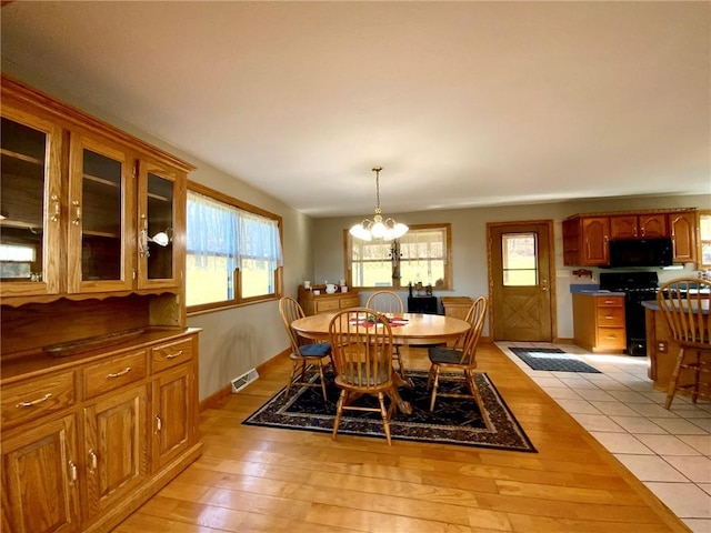 dining space featuring light hardwood / wood-style flooring, an inviting chandelier, and a healthy amount of sunlight