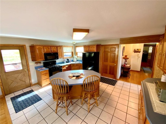 kitchen featuring black appliances, plenty of natural light, and light tile patterned flooring