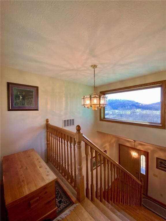 staircase with hardwood / wood-style floors and a notable chandelier