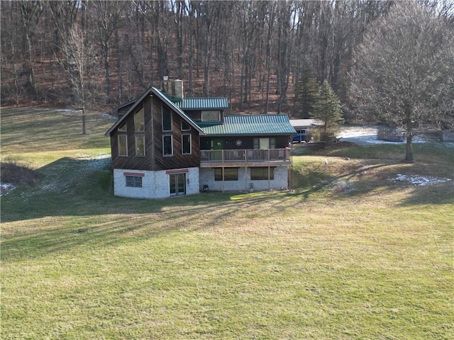 rear view of house featuring a balcony and a lawn