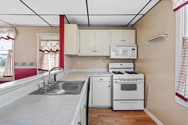 kitchen featuring white cabinetry, sink, a drop ceiling, and white appliances