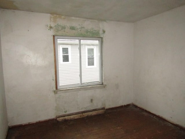 empty room with dark hardwood / wood-style flooring and a baseboard radiator