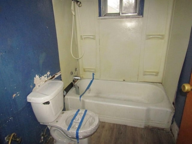 bathroom featuring shower / bathing tub combination, hardwood / wood-style flooring, and toilet