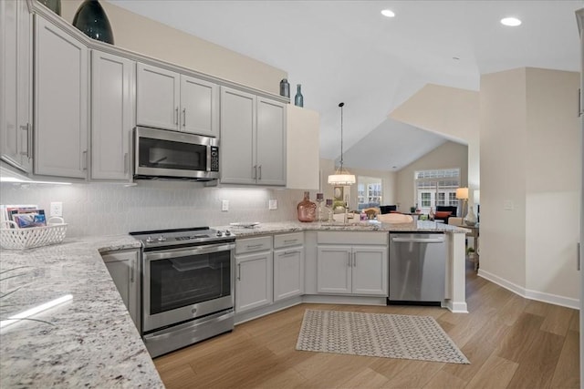 kitchen with sink, vaulted ceiling, light hardwood / wood-style floors, light stone counters, and stainless steel appliances