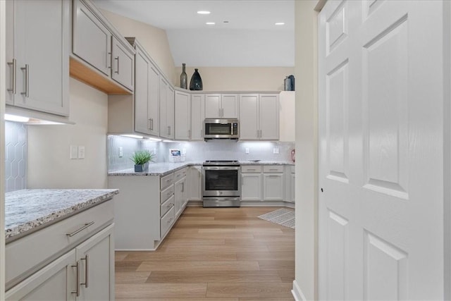 1111 Forest Oaks Dr, Center Twp, PA 16001 - kitchen featuring stainless steel appliances, light wood-style flooring, decorative backsplash, light stone counters, and recessed lighting