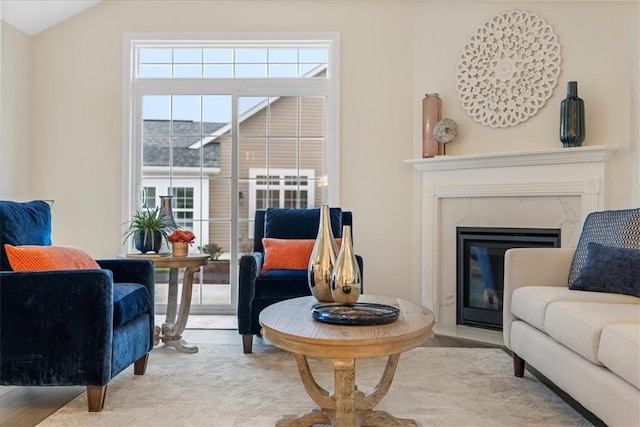 living area with a fireplace, light hardwood / wood-style flooring, and vaulted ceiling