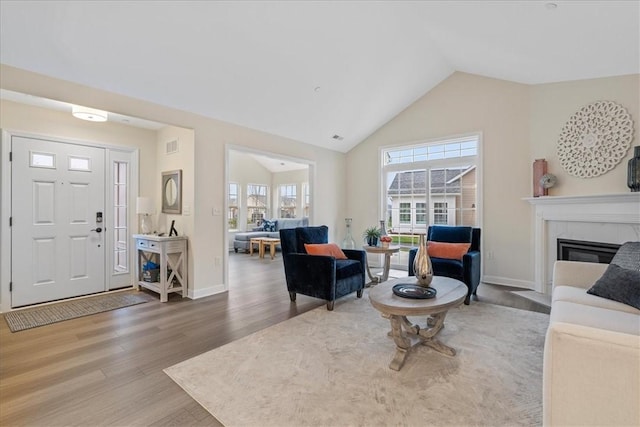 living room with a tile fireplace, hardwood / wood-style flooring, and lofted ceiling