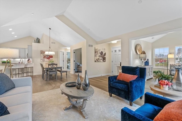 living room with light hardwood / wood-style floors, lofted ceiling, and sink