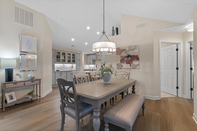 dining space featuring light wood-type flooring and vaulted ceiling