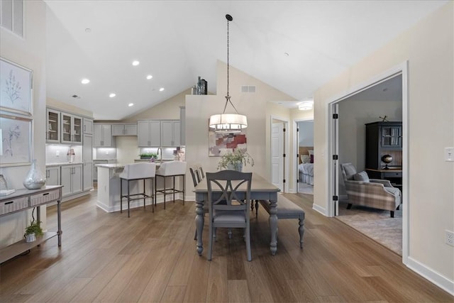 dining room with hardwood / wood-style flooring, high vaulted ceiling, and sink