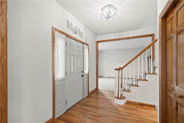 entryway with light hardwood / wood-style flooring and a notable chandelier