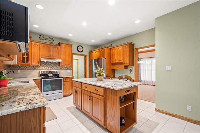 kitchen with light stone countertops, sink, stainless steel appliances, light tile patterned floors, and a kitchen island