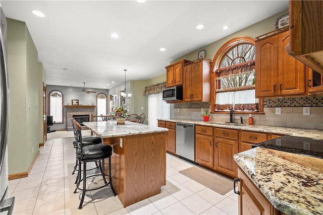 kitchen featuring pendant lighting, a center island, ceiling fan with notable chandelier, sink, and stainless steel appliances