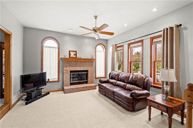 carpeted living room featuring ceiling fan and a brick fireplace