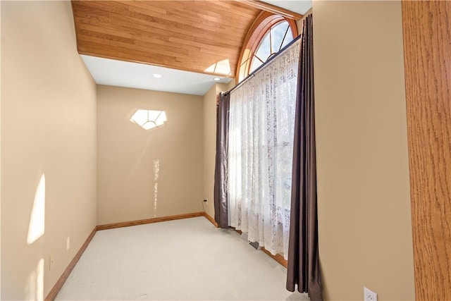 carpeted empty room featuring wooden ceiling and vaulted ceiling