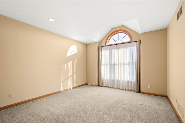 spare room featuring light carpet, plenty of natural light, and lofted ceiling