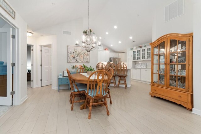 dining room featuring high vaulted ceiling, light hardwood / wood-style floors, and a notable chandelier