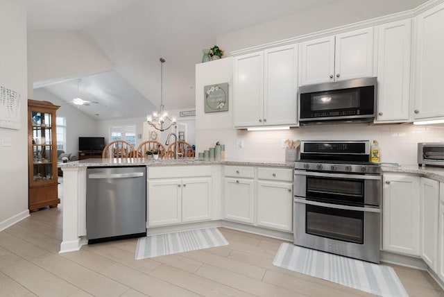 kitchen featuring backsplash, white cabinetry, ceiling fan with notable chandelier, and appliances with stainless steel finishes