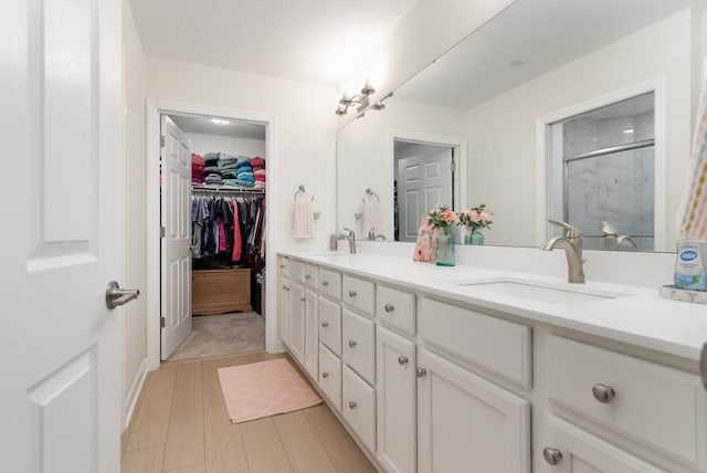 bathroom with wood-type flooring, vanity, and an enclosed shower