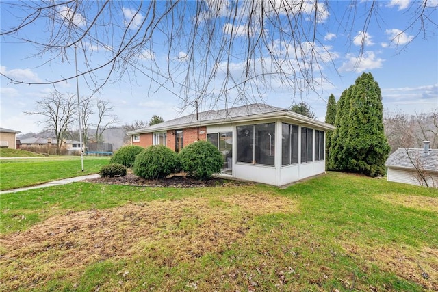 back of house featuring a lawn and a sunroom