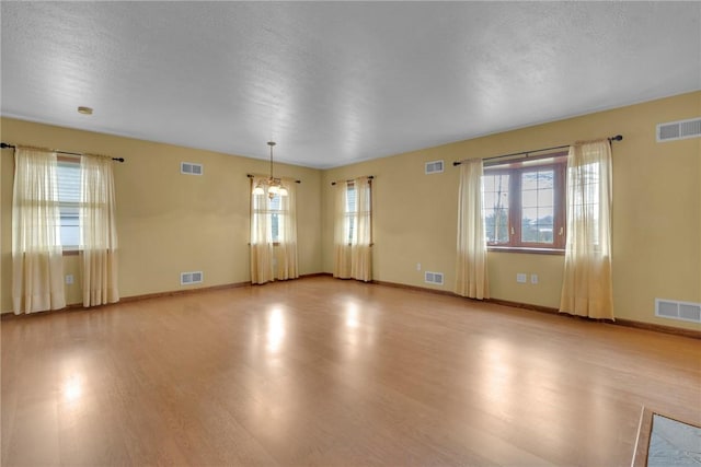 spare room with light hardwood / wood-style flooring, plenty of natural light, and a notable chandelier