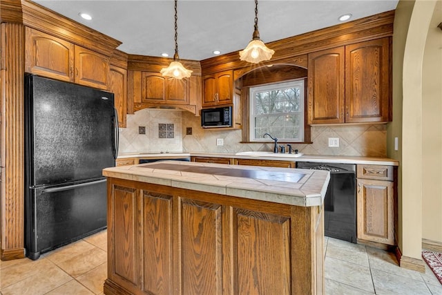 kitchen with a center island, sink, pendant lighting, light tile patterned floors, and black appliances