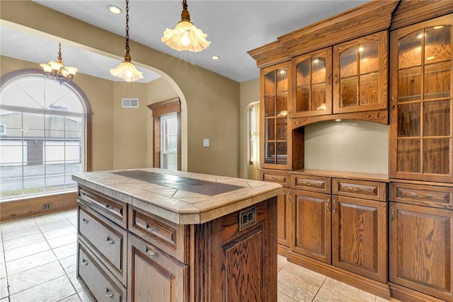 kitchen with decorative light fixtures, a chandelier, a center island, tile counters, and light tile patterned flooring