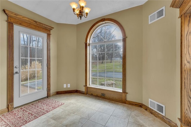 entryway with an inviting chandelier, a wealth of natural light, and light tile patterned flooring