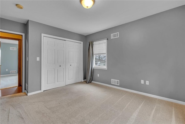 unfurnished bedroom featuring light carpet and a closet