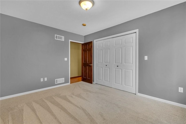 unfurnished bedroom featuring light carpet and a closet