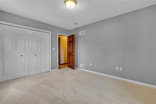 unfurnished bedroom featuring light carpet and a closet