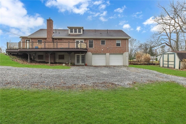 back of house with a garage, a yard, a wooden deck, and a storage shed