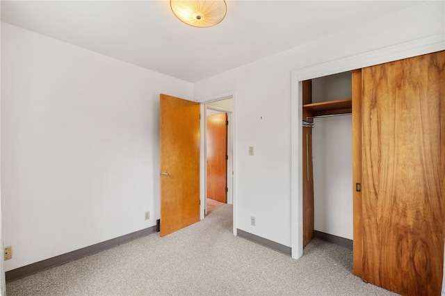 unfurnished bedroom featuring light colored carpet and a closet