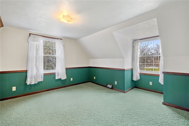 additional living space featuring carpet flooring, a healthy amount of sunlight, and vaulted ceiling