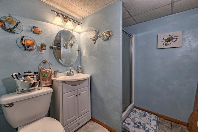 bathroom featuring an enclosed shower, a drop ceiling, vanity, tile patterned flooring, and toilet