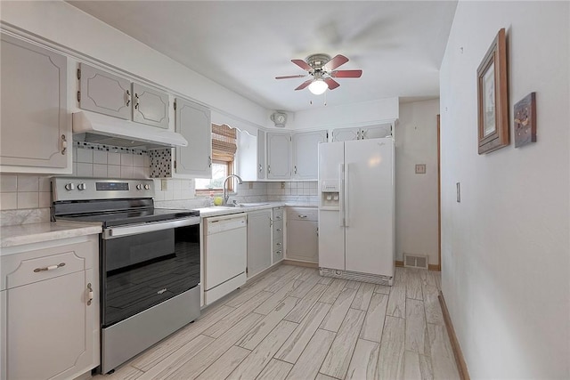 kitchen featuring light wood-type flooring, tasteful backsplash, white appliances, ceiling fan, and sink