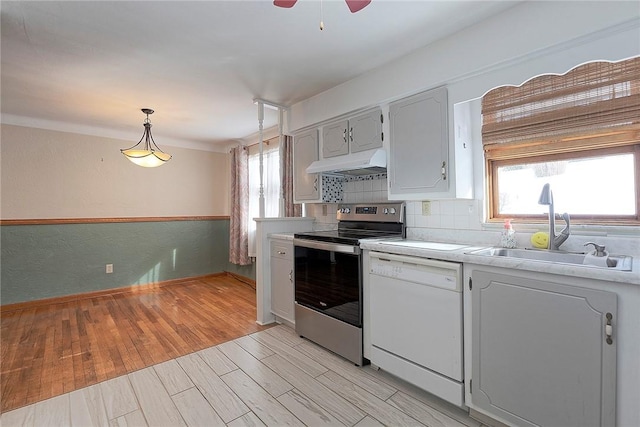 kitchen featuring white dishwasher, sink, light hardwood / wood-style flooring, hanging light fixtures, and stainless steel electric range