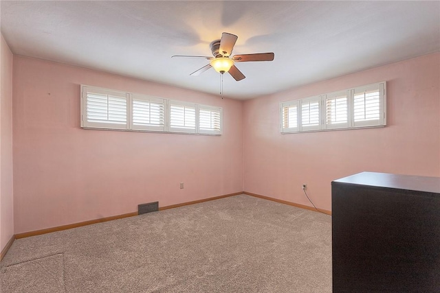 carpeted spare room with ceiling fan and plenty of natural light