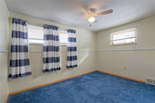 empty room with ceiling fan and dark carpet