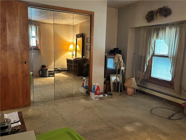 miscellaneous room with a textured ceiling, carpet floors, a baseboard radiator, and a wealth of natural light