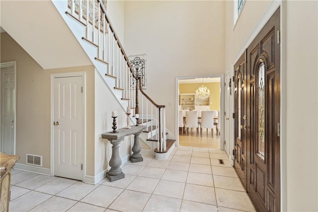 tiled foyer with a high ceiling and a chandelier