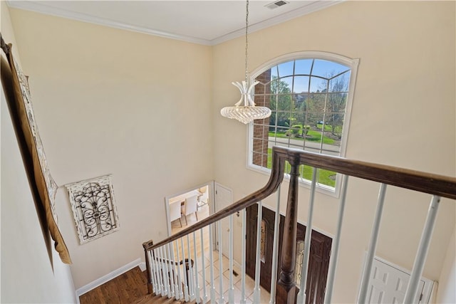 staircase with wood-type flooring, ornamental molding, and a notable chandelier